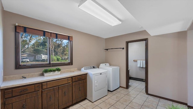 clothes washing area featuring washing machine and dryer, cabinet space, light tile patterned flooring, and baseboards
