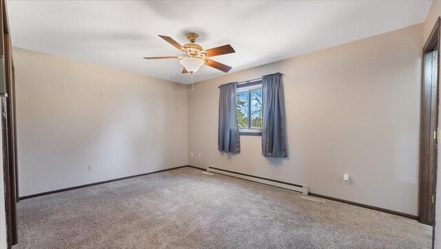 carpeted spare room featuring baseboard heating, a ceiling fan, and baseboards