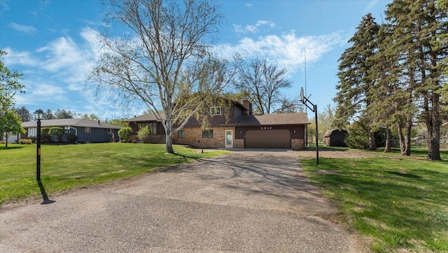 view of front of property with driveway, an attached garage, a front yard, a chimney, and brick siding
