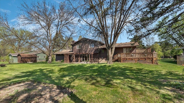 back of house featuring a deck, a lawn, an outbuilding, and a storage unit