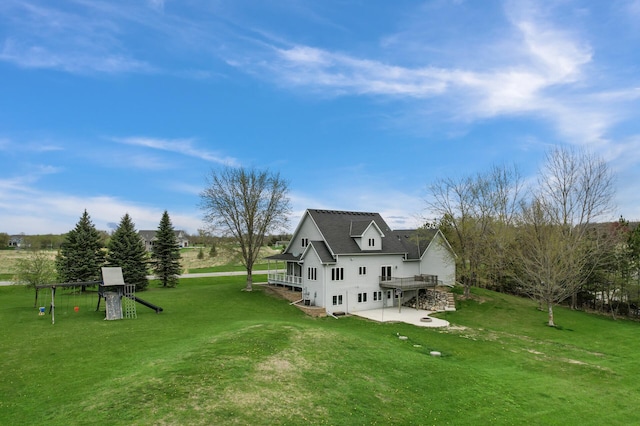 view of side of home with a lawn, a wooden deck, a playground, and a patio