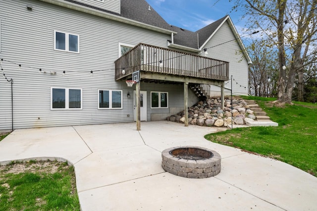 rear view of house with roof with shingles, a deck, stairway, a patio area, and a fire pit