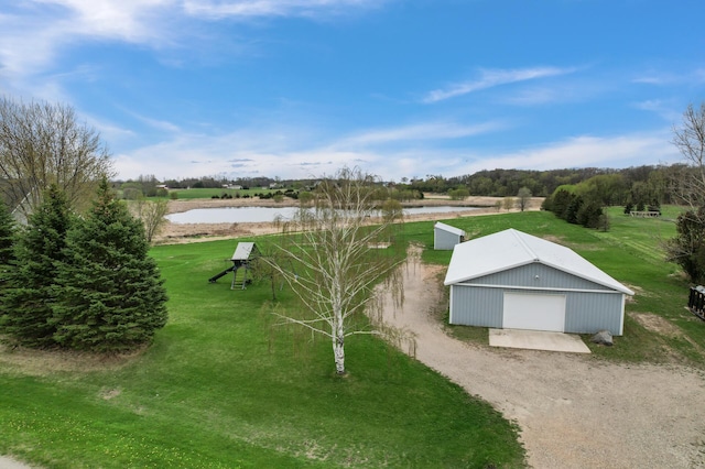 view of home's community featuring a detached garage, a water view, a yard, and an outdoor structure