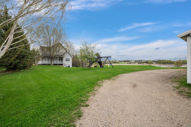exterior space with a lawn, dirt driveway, and a playground
