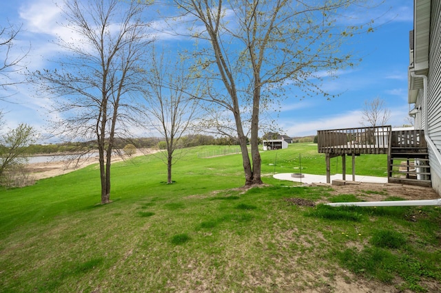 view of yard featuring a deck with water view and a patio