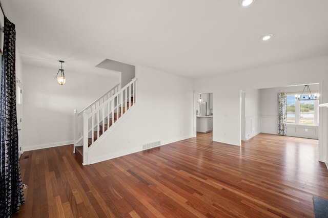 unfurnished living room featuring visible vents, wood finished floors, stairway, a notable chandelier, and recessed lighting