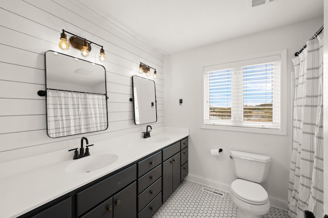 bathroom with a sink, baseboards, toilet, and double vanity