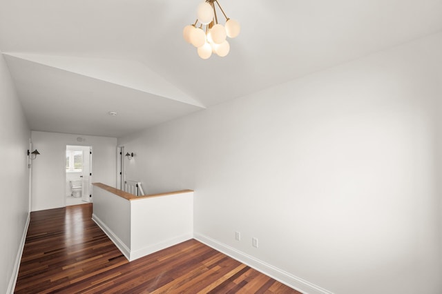 interior space with vaulted ceiling, dark wood finished floors, baseboards, an upstairs landing, and an inviting chandelier