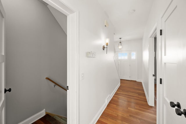 hallway with baseboards, an upstairs landing, visible vents, and hardwood / wood-style floors