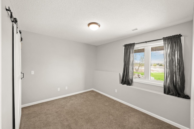 unfurnished room featuring carpet flooring, a textured ceiling, and a barn door