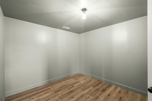 spare room with baseboards, visible vents, and wood finished floors
