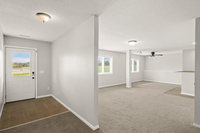 entrance foyer with ceiling fan, a textured ceiling, visible vents, baseboards, and carpet