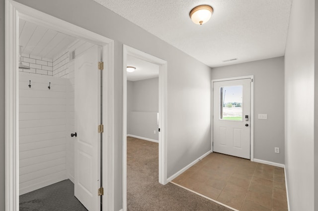 interior space with a textured ceiling, baseboards, and visible vents