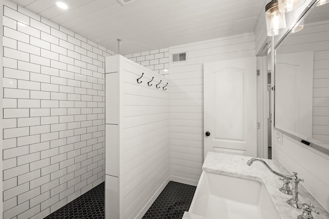 bathroom featuring walk in shower, tile patterned floors, visible vents, and a sink