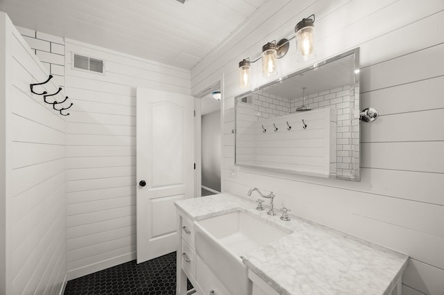 bathroom featuring vanity, tile patterned flooring, wood walls, and visible vents