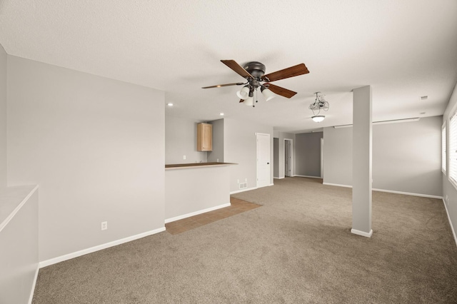 unfurnished living room featuring carpet floors, baseboards, and a ceiling fan