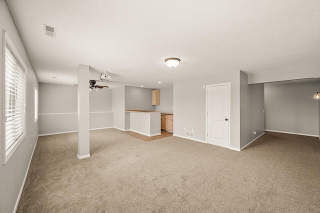 basement with light colored carpet, baseboards, and ceiling fan