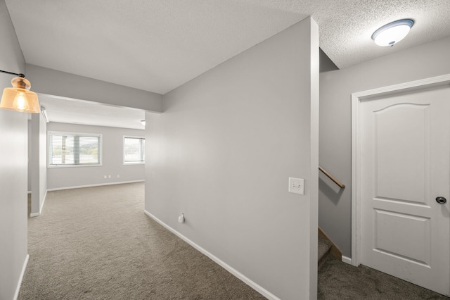 hall featuring carpet floors, baseboards, and an upstairs landing