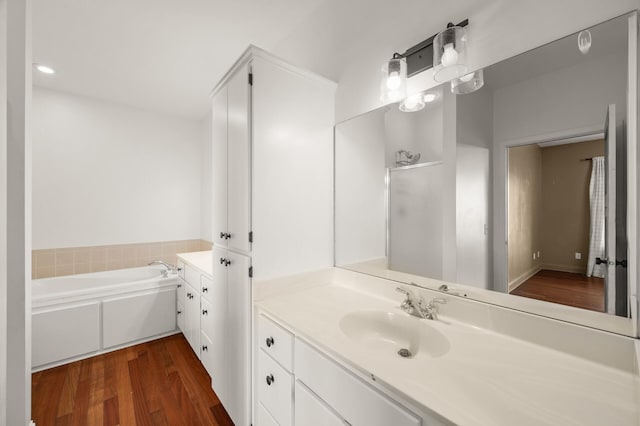 full bathroom featuring vanity, a garden tub, and wood finished floors