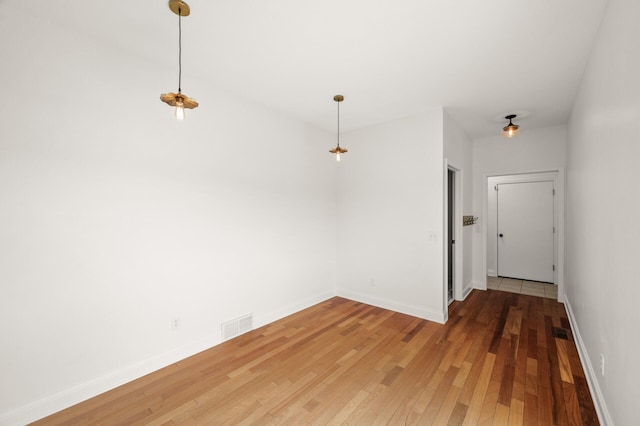 unfurnished dining area featuring baseboards, visible vents, and light wood-type flooring