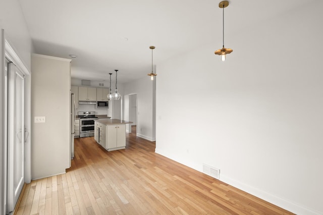 kitchen with visible vents, a center island, built in microwave, range with two ovens, and light wood-style flooring