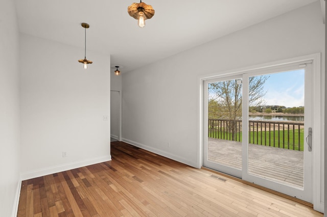 unfurnished room featuring a water view, baseboards, visible vents, and hardwood / wood-style flooring