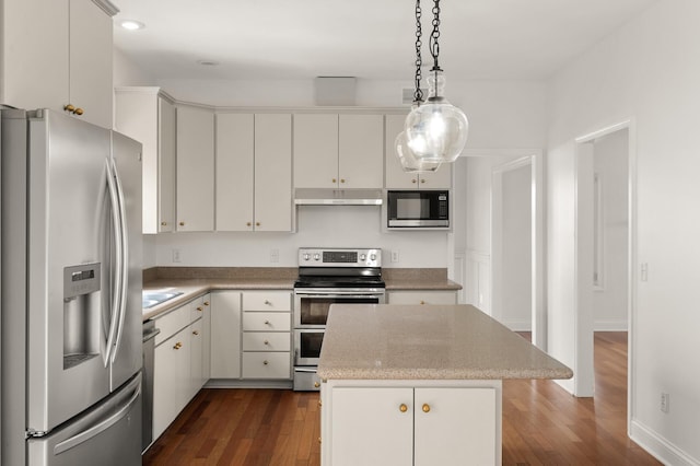 kitchen with appliances with stainless steel finishes, hanging light fixtures, under cabinet range hood, and dark wood-style floors