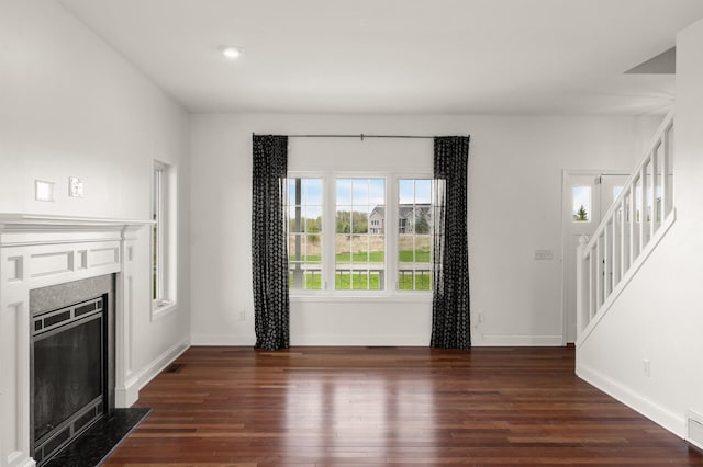 unfurnished living room featuring baseboards, a fireplace with flush hearth, and wood finished floors