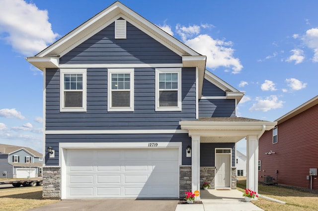 view of front of house featuring an attached garage, driveway, and stone siding