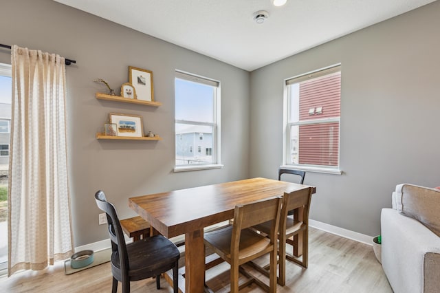 dining space featuring baseboards and light wood-style flooring