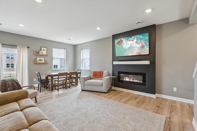 living room featuring a fireplace, baseboards, light wood-type flooring, recessed lighting, and a textured ceiling