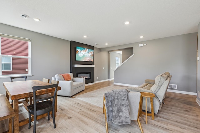 living room with visible vents, light wood-style floors, baseboards, recessed lighting, and a large fireplace