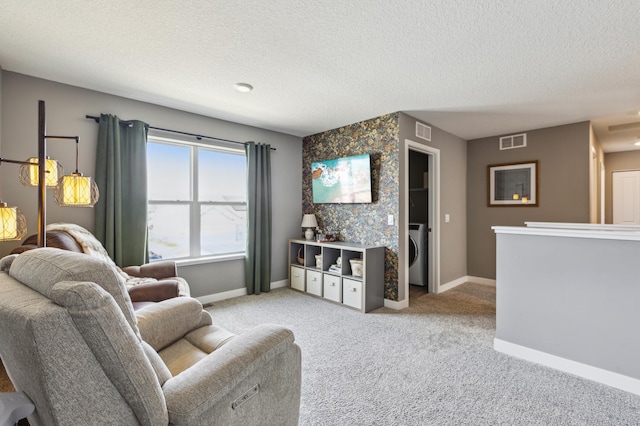 living area featuring a textured ceiling, washer / clothes dryer, and visible vents
