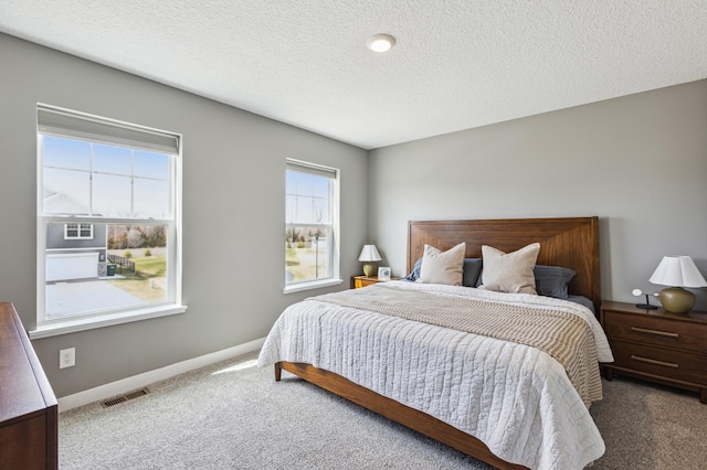 bedroom featuring baseboards, carpet flooring, a textured ceiling, and visible vents