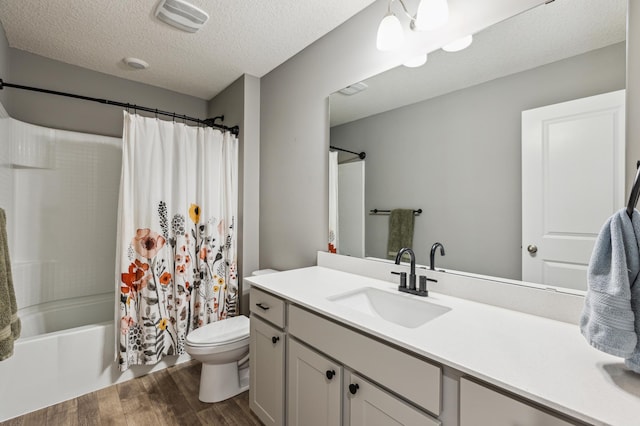 full bath featuring vanity, wood finished floors, toilet, shower / bathtub combination with curtain, and a textured ceiling