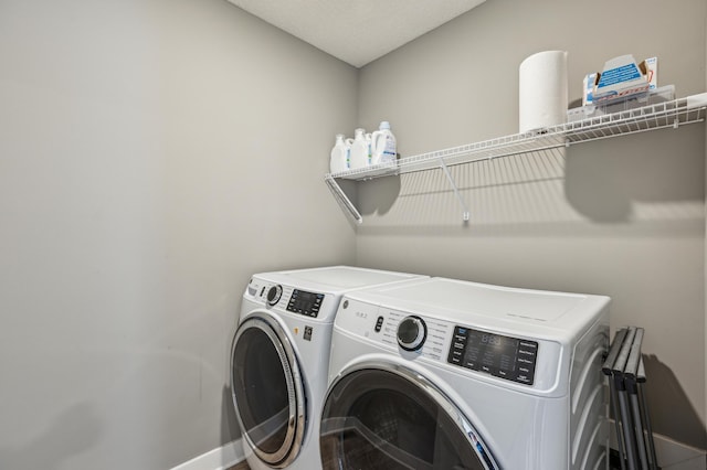 clothes washing area with laundry area, washer and clothes dryer, and baseboards