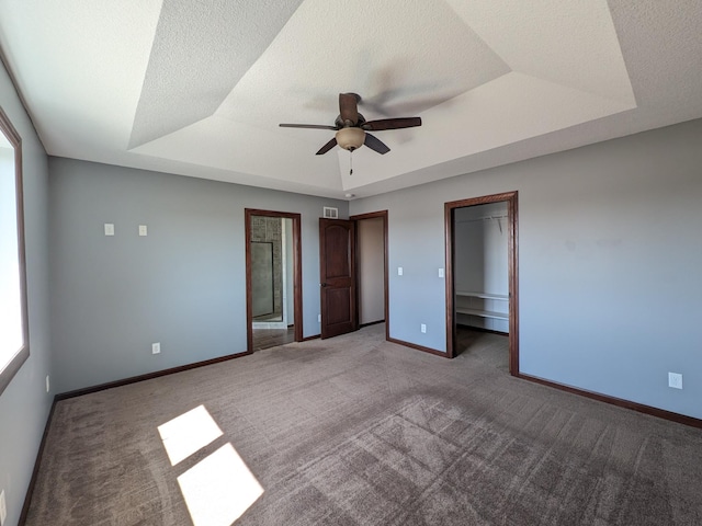 580 Canyon Ln NW, Eyota, MN 55934 - unfurnished bedroom featuring a tray ceiling, carpet floors, baseboards, and ceiling fan