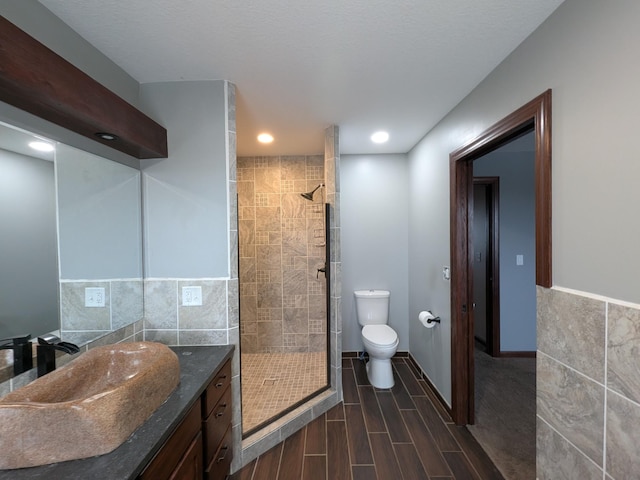 580 Canyon Ln NW, Eyota, MN 55934 - bathroom featuring a stall shower, toilet, vanity, tile walls, and wood finished floors