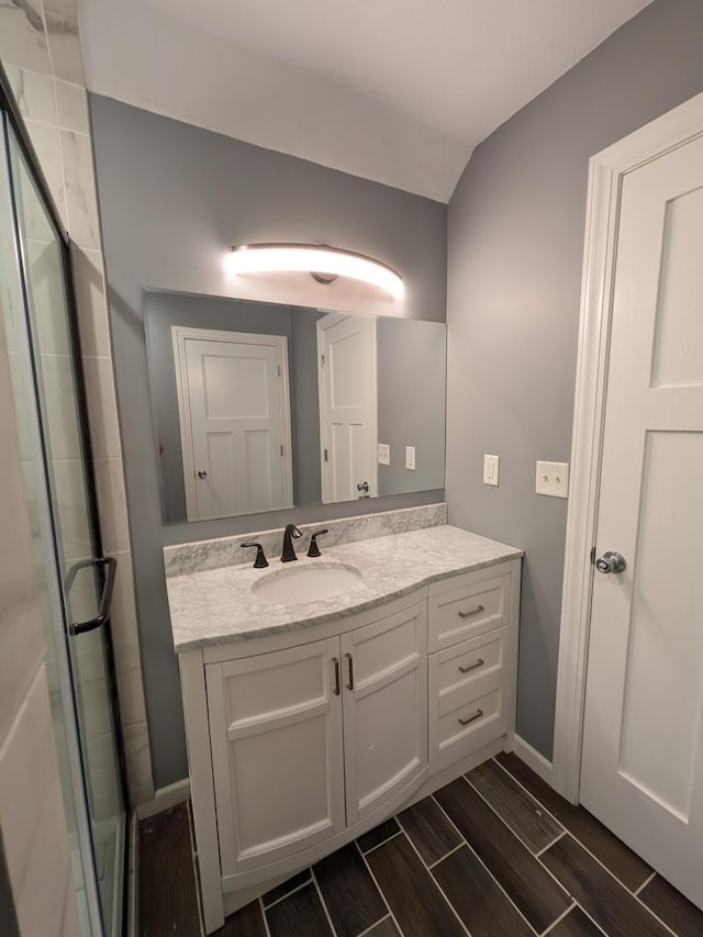 580 Canyon Ln NW, Eyota, MN 55934 - bathroom featuring vanity, a shower stall, wood finish floors, baseboards, and vaulted ceiling