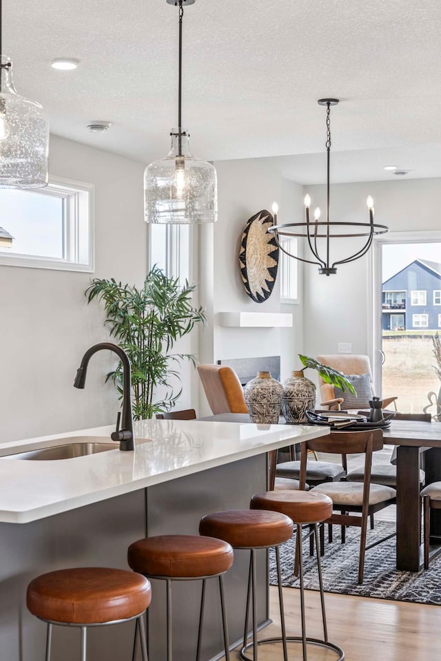 interior space with an inviting chandelier, wood finished floors, a textured ceiling, a sink, and hanging light fixtures
