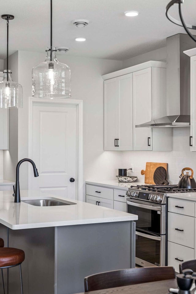 kitchen featuring wall chimney range hood, range with two ovens, a sink, and light countertops