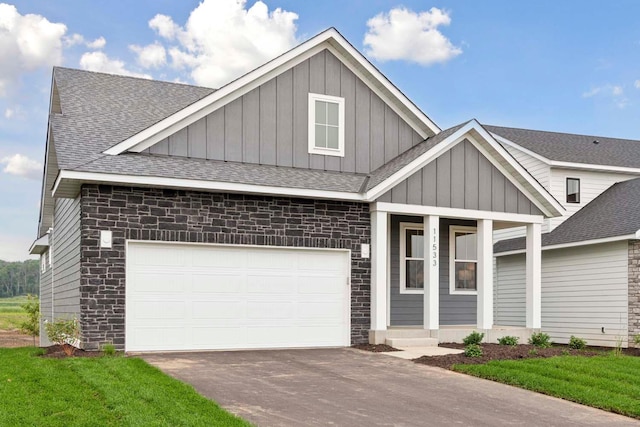 12439 Drayton Trl, Apple Valley, MN 55124 - view of front facade featuring board and batten siding, roof with shingles, driveway, a porch, and stone siding