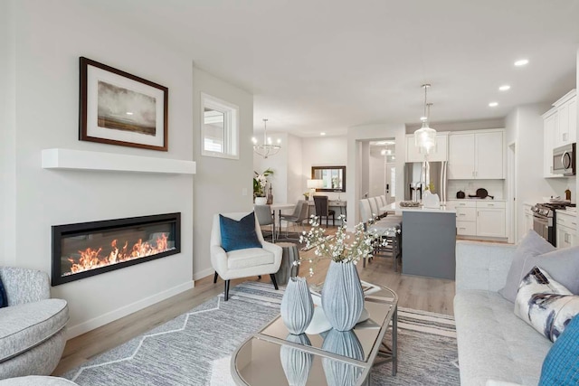 12439 Drayton Trl, Apple Valley, MN 55124 - living area with light wood-style flooring, recessed lighting, a glass covered fireplace, and a chandelier