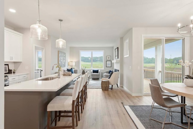 12439 Drayton Trl, Apple Valley, MN 55124 - kitchen with light wood-type flooring, white cabinets, light countertops, pendant lighting, and open floor plan