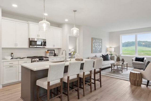 12439 Drayton Trl, Apple Valley, MN 55124 - kitchen with stainless steel appliances, light wood finished floors, open floor plan, a breakfast bar area, and a kitchen island with sink