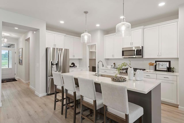 12439 Drayton Trl, Apple Valley, MN 55124 - kitchen with appliances with stainless steel finishes, a kitchen breakfast bar, light wood-style flooring, white cabinets, and recessed lighting