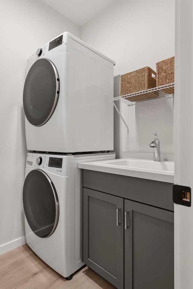 12439 Drayton Trl, Apple Valley, MN 55124 - laundry room with stacked washing machine and dryer, cabinet space, and light wood-style floors