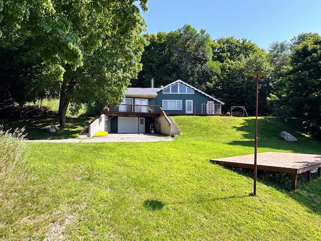 exterior space with a lawn, an attached garage, and a wooden deck