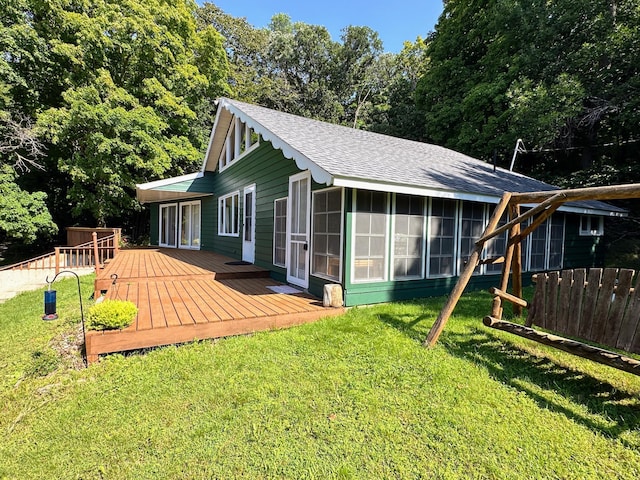 back of house featuring roof with shingles, a deck, a sunroom, fence, and a yard