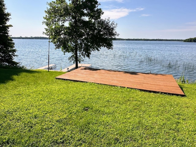 view of dock featuring a lawn and a water view